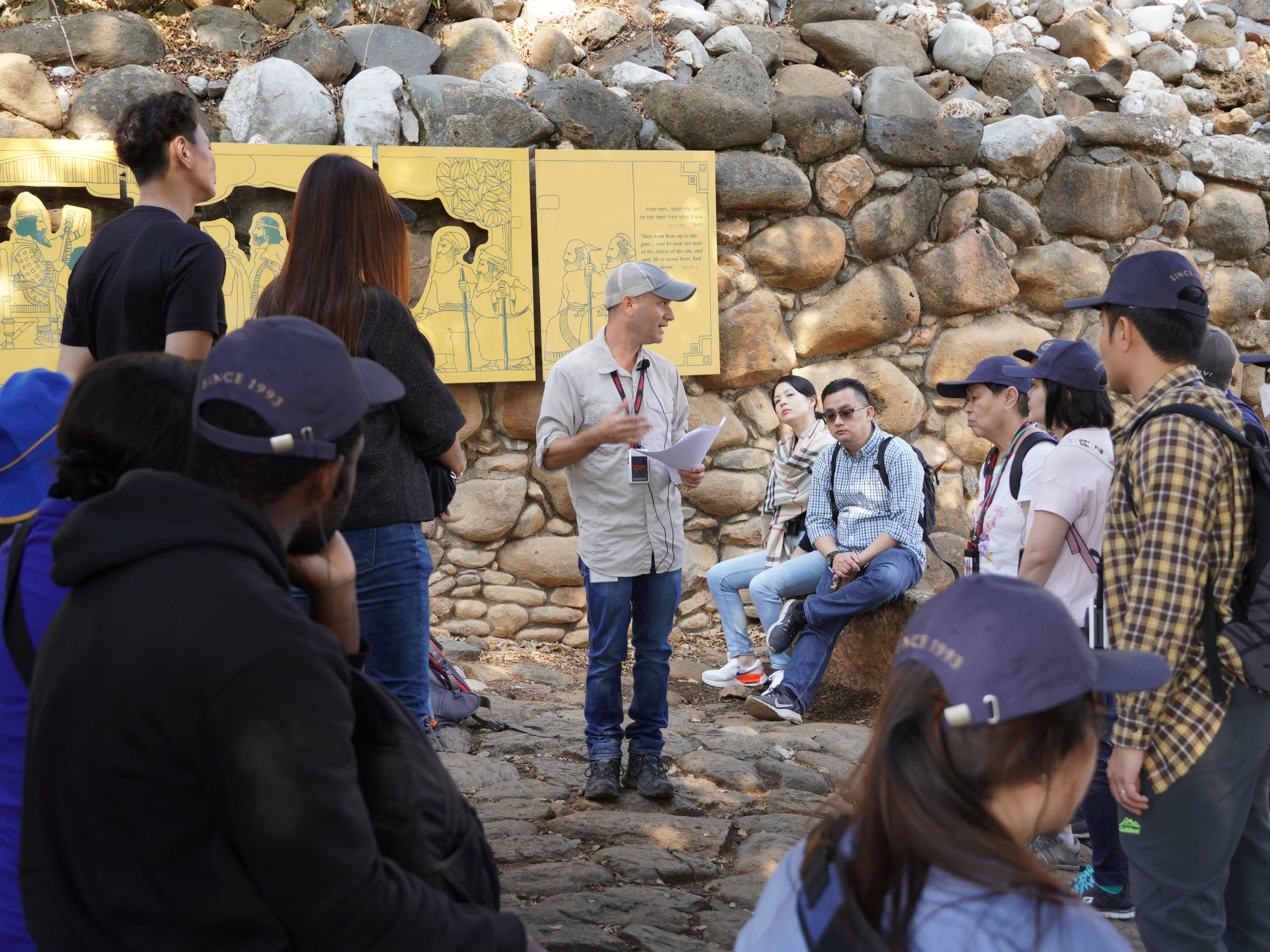 Ran Frenkel explaining a biblical text to a tour group beside the ancient stone ruins at Tel Dan