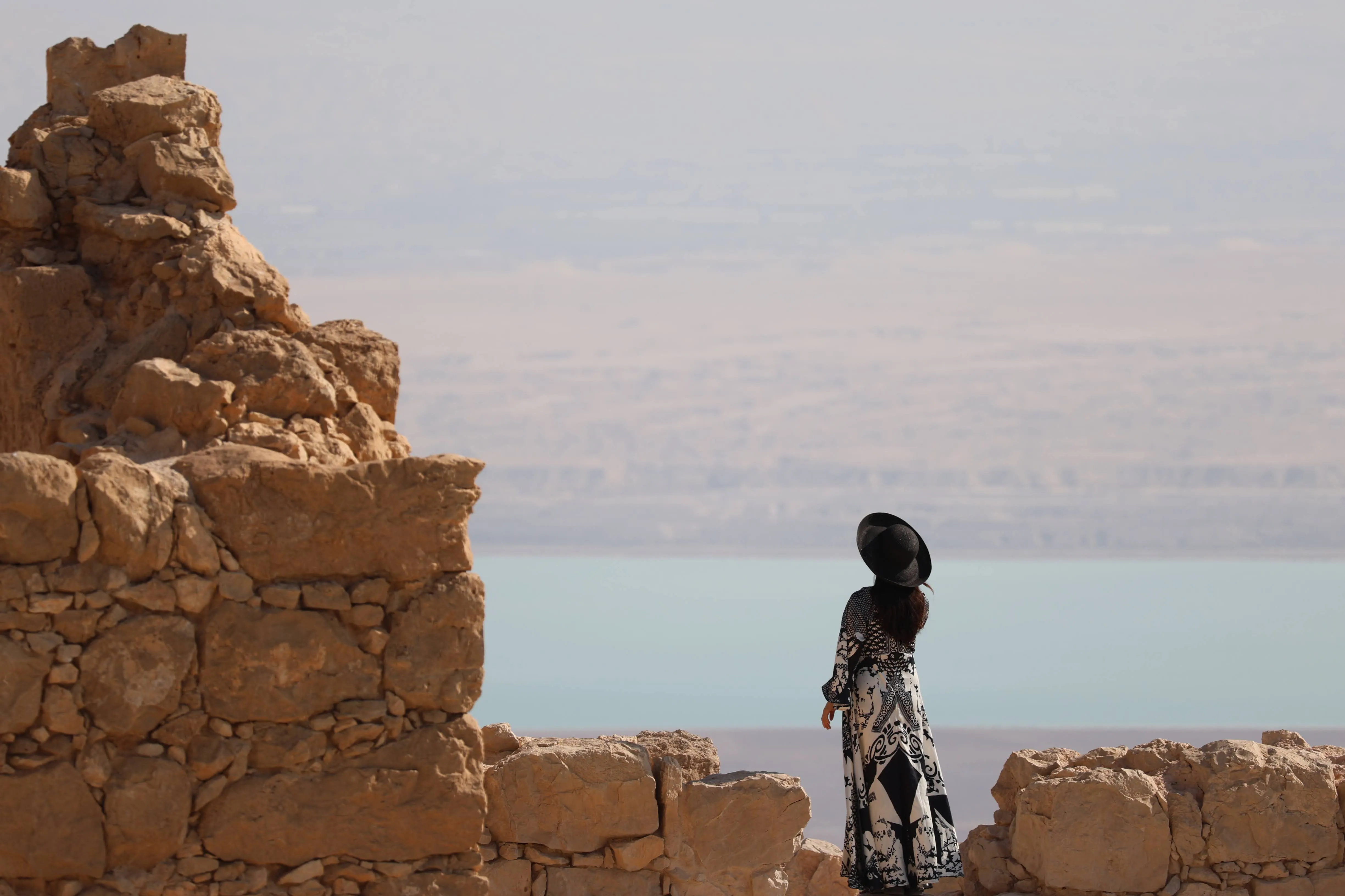 A traveler looking out over the Dead Sea from the cliffs of Masada, on a private day tour in Israel.