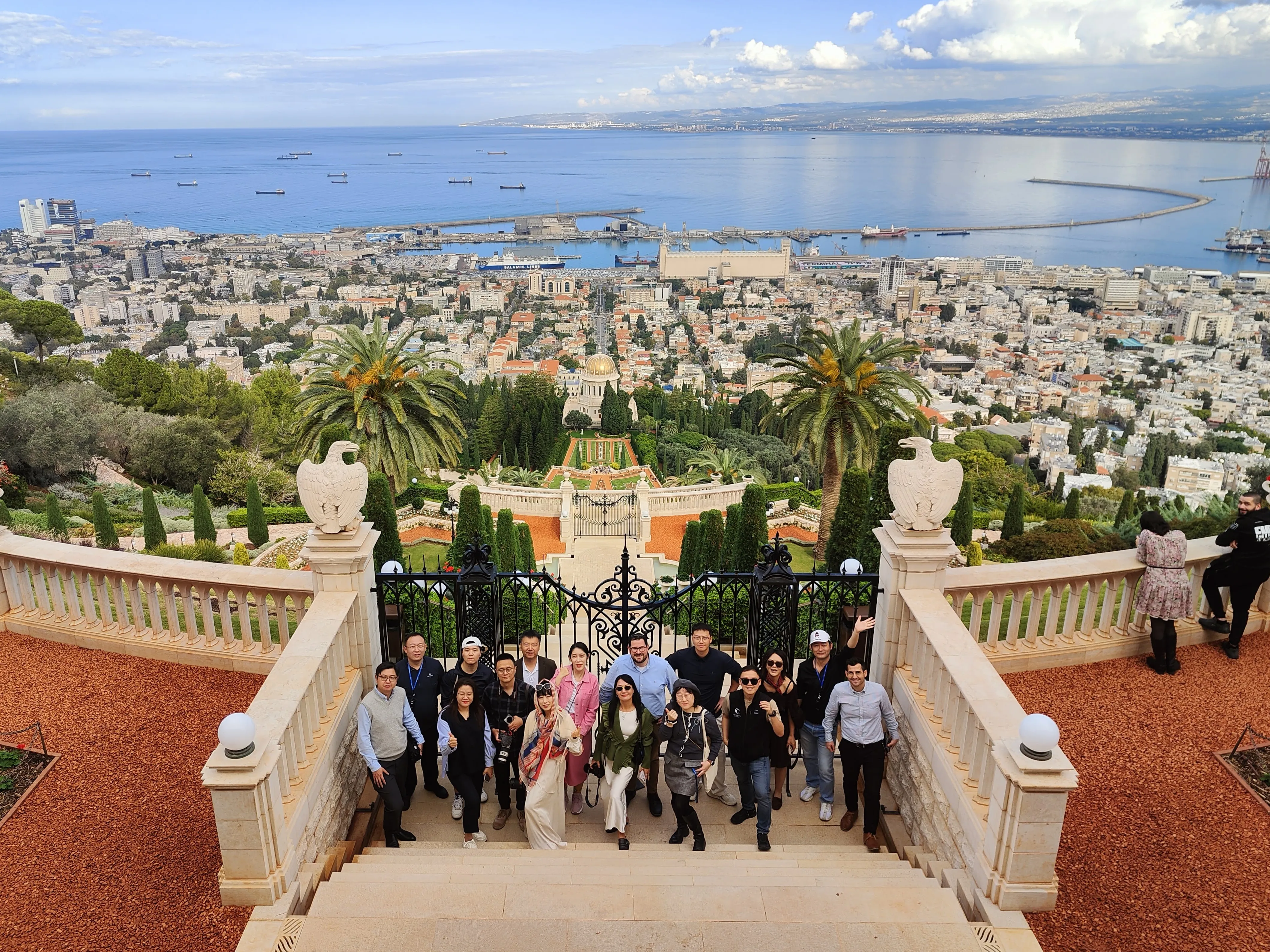 A tour group on the stairs of the Bahá'í Gardens in Haifa, with the shrine, terraced gardens, the city, and the bay stretching to the horizon, on a private multi-day journey in Israel.